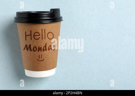 Inizi la sua settimana con buon umore. Tazza di carta con frase Ciao Lunedi su sfondo azzurro, vista dall'alto Foto Stock