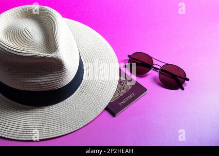 Cappello Panama in paglia con passaporto e occhiali da sole isolati su sfondo rosa Foto Stock