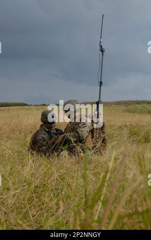 STATI UNITI Corpo marino Sgt. Christopher Lee, sinistra, e Lance CPL. Ardean Nicolas, destra, entrambi i linguisti crittologici con Battalion Landing Team 1/4, 31st Marine Expeditionary Unit, ha stabilito le comunicazioni durante un esercizio di raid in elicottero su cioè Shima, Okinawa, Giappone, 9 febbraio 2023. I Marines di BLT 1/4 sono stati incaricati di catturare e assicurare punti obiettivo da forze nemiche simulate durante l'esercizio. Il MEU 31st opera a bordo di navi del gruppo USS America Amphibious Ready nel settore delle operazioni della flotta 7th per migliorare l'interoperabilità con alleati e partner e servire come risposta pronta Foto Stock