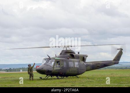 Moncton, NB, Canada - 23 agosto 2014: Un soldato dà a un elicottero Griffon CH-146 un pollice di distanza per il decollo. Il cielo è nuvoloso. Foto Stock