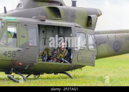 Moncton, NB, Canada - 23 agosto 2014: Soldato prende un pisolino in un elicottero Griffon. L'elicottero è in erba con la porta laterale aperta. Foto Stock