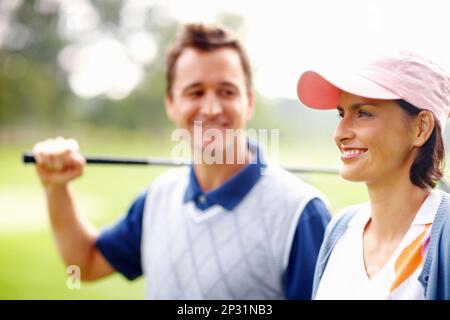 Carino golfer sorridente. Primo piano di donna carina sorridente con un uomo che tiene un randello di golf. Foto Stock