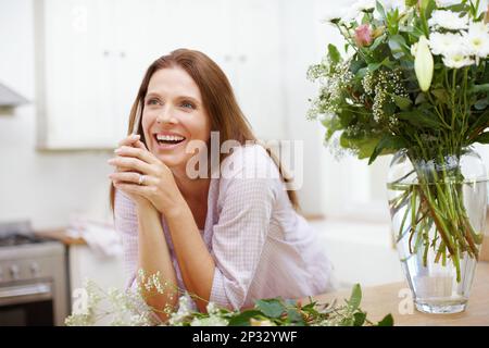 Entusiasta di vedere la sua ultima creazione di fiori. Una bella donna nel processo di organizzazione di un bouquet di fiori. Foto Stock