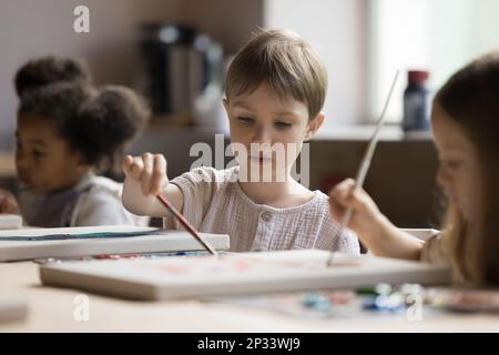 Concentrato carino bambino disegno su classe in gruppo di compagni di classe Foto Stock