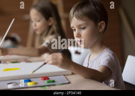 Serio fidanzato bambino dipinto su tela, utilizzando pennello Foto Stock