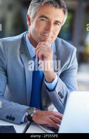 Ha pianificato la sua salita aziendale con attenzione. Ritratto di un uomo d'affari maturo dall'aspetto sicuro che lavora su un notebook. Foto Stock