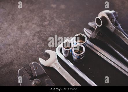 Utensili manuali composti da chiavi, pinze, chiavi a bussola, disposti su vecchio fondo in lamiera d'acciaio. Foto Stock