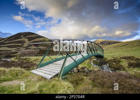 Ponte pedonale in metallo sul fiume di Glen, al sole serale, Clunie Water, vicino a Braemar, Cairngorms N. P. Aberdeenshire, Highlands, Scozia, United Foto Stock
