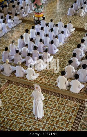 I discepoli di Caodaist seduti durante la cerimonia, il tempio di Cao dai, la Santa sede di Tay Ninh, Tay Ninh, Provincia di Tay Ninh, Vietnam Foto Stock