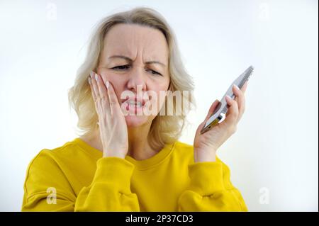 Dentifricio donna tenendo la mano sulla guancia rugosa fronte molto sconvolto chiamata medico prendere appuntamento con il dentista bianco studio spazio per testo bustard tuta Foto Stock