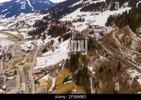 Fotografia in drone del pendio del cielo di montagna, del ponte ferroviario che va sopra il pendio e degli impianti di risalita del cielo durante la giornata nuvolosa di inverno Foto Stock