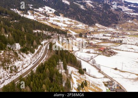 Fotografia del drone di ferrovia che va sopra la montagna e treno durante il giorno nuvoloso di inverno Foto Stock