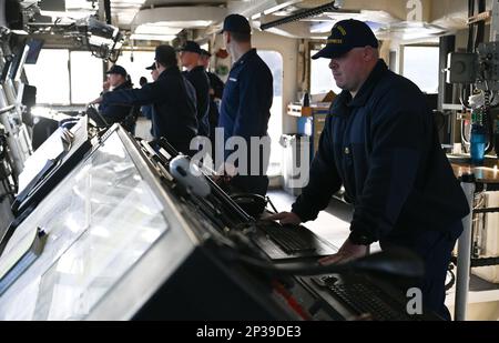 I membri dell'equipaggio a bordo della Guardia Costiera Cutter Cypress lavorano insieme per pilotare la gara di Buoy di 225 piedi di Juniper Class attraverso Womens Bay a Kodiak, Alaska, 11 gennaio 2023. L'equipaggio Cypress ricopre il ruolo di "Custode Aleutiano" e si occupa della manutenzione degli ausili alla navigazione attraverso Kodiak e la catena Aleutiana. STATI UNITI Foto della Guardia Costiera di Petty Officer 3rd Classe Ian Gray. Foto Stock