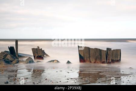 Resti di antiche difese marine sulla costa utilizzando una lunga esposizione in inverno sulla costa Norfolk a Happisburgh, Norfolk, Inghilterra, Regno Unito. Foto Stock