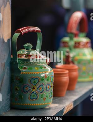 Una foto verticale di vivaci ceramiche esposte in modo artistico su uno scaffale in un ambiente caldo Foto Stock