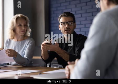 Un uomo serio e impegnato leader di start-up aziendale che parla con i colleghi Foto Stock