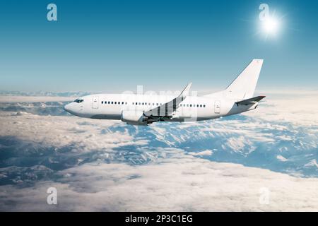 Aereo passeggeri bianco che vola in aria su montagne innevate Foto Stock