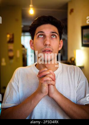 Il giovane uomo che implorava con le mani si unì alla preghiera Foto Stock