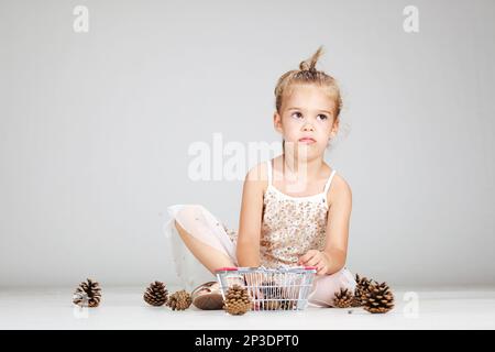 piccola ragazza caucasica che gioca con i pinecones Foto Stock