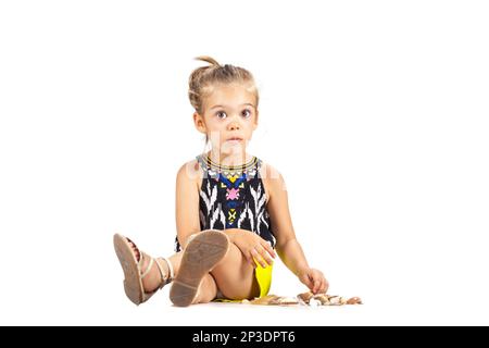 piccola ragazza caucasica che gioca con le conchiglie Foto Stock