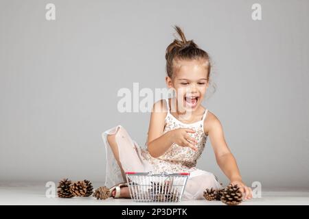 piccola ragazza caucasica che gioca con i pinecones Foto Stock