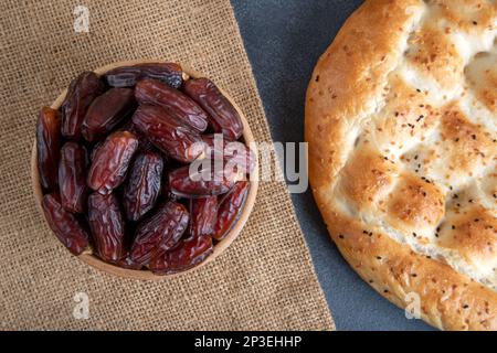 Frutta di data in ciotola di legno su sfondo nero, vista dall'alto Foto Stock