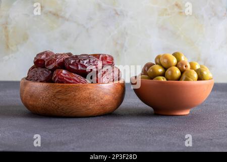 Datteri frutta e olive verdi su uno sfondo nero.Tavola tradizionale iftar Foto Stock