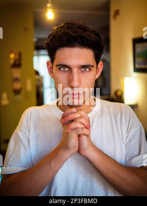 Il giovane uomo che implorava con le mani si unì alla preghiera Foto Stock