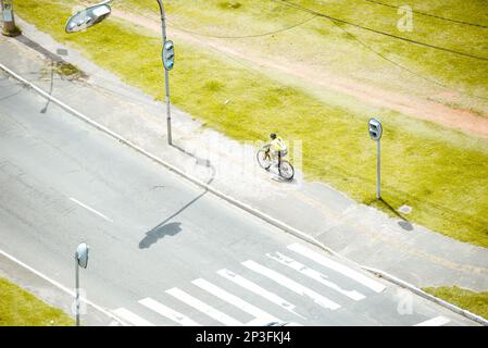 Ciclista che passa attraverso la corsia dell'automobile nel quartiere di Pernambues in Salvador, Bahia. Foto Stock