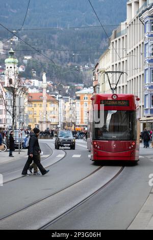 Un tram attraversa la strada nella città storica di Innsbruck, situata in una valle di montagne innevate Foto Stock