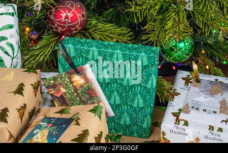 Un primo piano di un mucchio di regali di Natale avvolti che giacciono sotto l'albero di Natale. Sono avvolti in differenti carte da imballaggio a motivi. Foto Stock