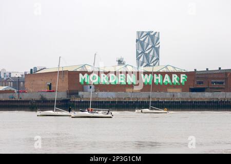 Si affaccia sul fiume Tamigi a Londra fino a Morden Wharf. Tre yacht bianchi navigano lungo il fiume. Dietro c'è l'enorme opera d'arte Optic Cloak. Foto Stock