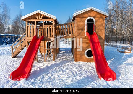 scivolo in legno nel parco per bambini in inverno. scivolo per bambini vuoto. parco per bambini in inverno Foto Stock