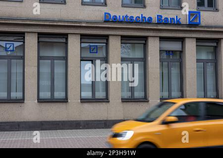 Neuwied, Germania - 17 dicembre 2021: Facciata dell'ufficio locale della Deutsche Bank con un'auto gialla in movimento sfocato di fronte. Deutsche Bank AG è una società tedesca Foto Stock