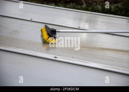 Lavaggio del copricapo pergolato in alluminio. rimuovere le alghe sporche con sapone a spazzola e acqua vicino in giardino da una terrazza casa Foto Stock