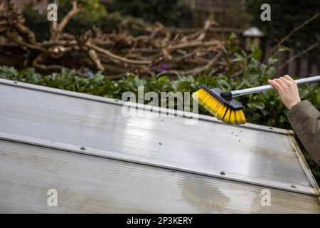 Lavaggio del copricapo pergolato in alluminio. rimuovere le alghe sporche con sapone a spazzola e acqua vicino in giardino da una terrazza casa Foto Stock