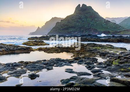 L'aspra costa di Punta del Hidalgo all'alba. Con le montagne di Anaga sullo sfondo, Tenerife, Isole Canarie Foto Stock