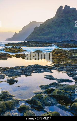 L'aspra costa di Punta del Hidalgo all'alba. Con le montagne di Anaga sullo sfondo, Tenerife, Isole Canarie Foto Stock