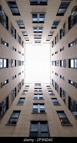 Luce alla fine del tunnel. Vista astratta verso l'alto del cortile dell'edificio di New York City che si apre sul cielo sovraesposto. Grandangolo, 16:9 mm verticale Foto Stock