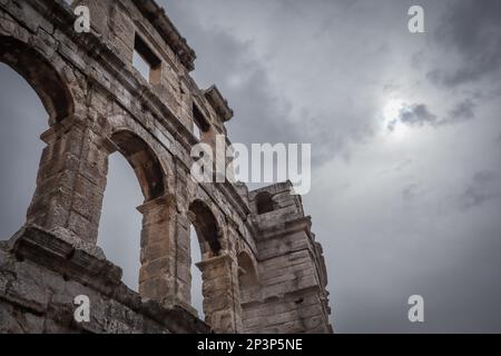 Pula Arena con cielo nuvoloso. Sotto Vista dell'architettura storica delle rovine in Croazia. Anfiteatro Romano in Europa con cielo nuvoloso. Foto Stock