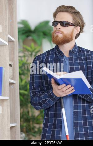 un uomo cieco che legge un libro scritto in braille a casa Foto Stock