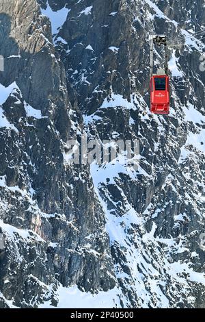 Funivia rossa di Lomnický štít che sale sulla scogliera di montagna degli alti Tatra sopra Skalnaté Pleso e Tatranská Lomnica in inverno in alta forma Foto Stock