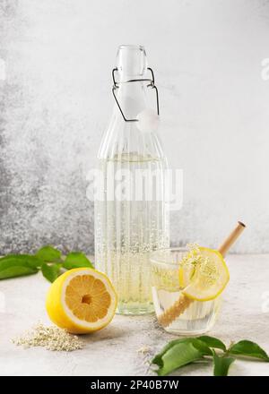 Limonata di fiori di elderfiore fatta in casa in bottiglia di vetro. Drink estivo con fiore di sambuco e limone. Concetto di bevande biologiche. Messa a fuoco selettiva. Spazio di copia. Foto Stock