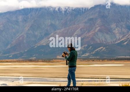 I turisti scattano foto lungo l'autostrada dell'Alaska durante l'autunno, con paesaggi mozzafiato sullo sfondo. Foto Stock