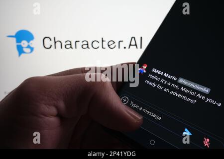 Esempio di chatbot ai del personaggio visualizzato sullo schermo dello smartphone. Carattere sfocato.ai logo sullo sfondo. Stafford, Regno Unito, 5 marzo 2023 Foto Stock