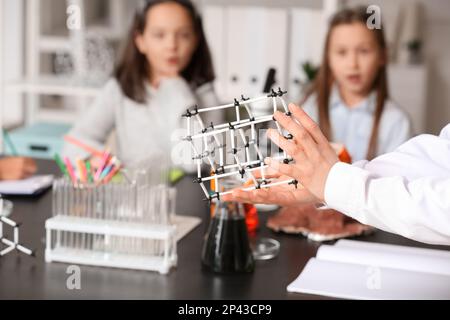 Insegnante con modello molecolare che conduce la lezione ai bambini piccoli in classe di scienza, primo piano Foto Stock