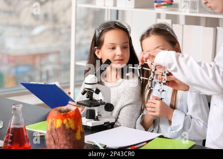 Insegnante di chimica con modello molecolare che conduce una lezione alle bambine in classe scientifica Foto Stock