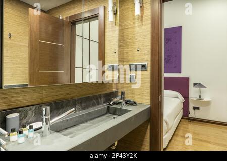 Bagno bello e moderno con lavandino in marmo nero con due ante e uscita per una camera da letto matrimoniale Foto Stock