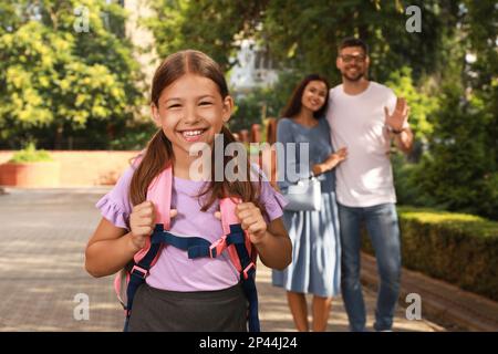 I genitori salutano la loro figlia prima di andare a scuola all'aperto Foto Stock