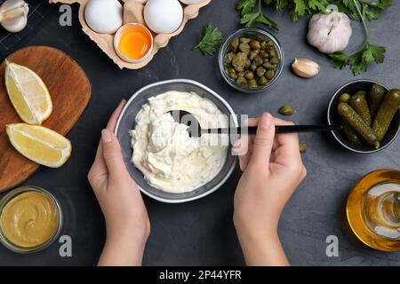 Donna con salsa tartara al tavolo nero, vista dall'alto Foto Stock